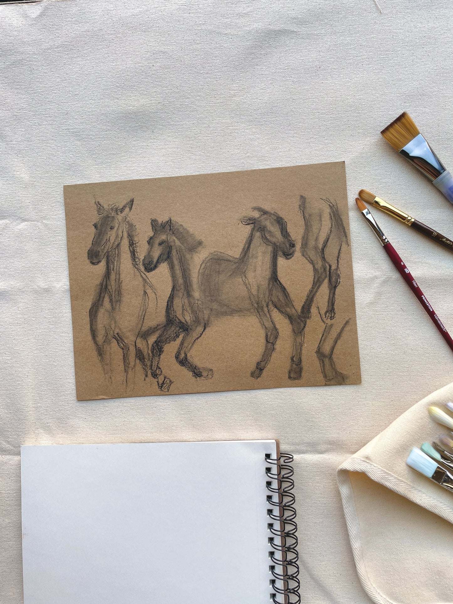 Pencil and charcoal drawing of horses in motion on natural paper