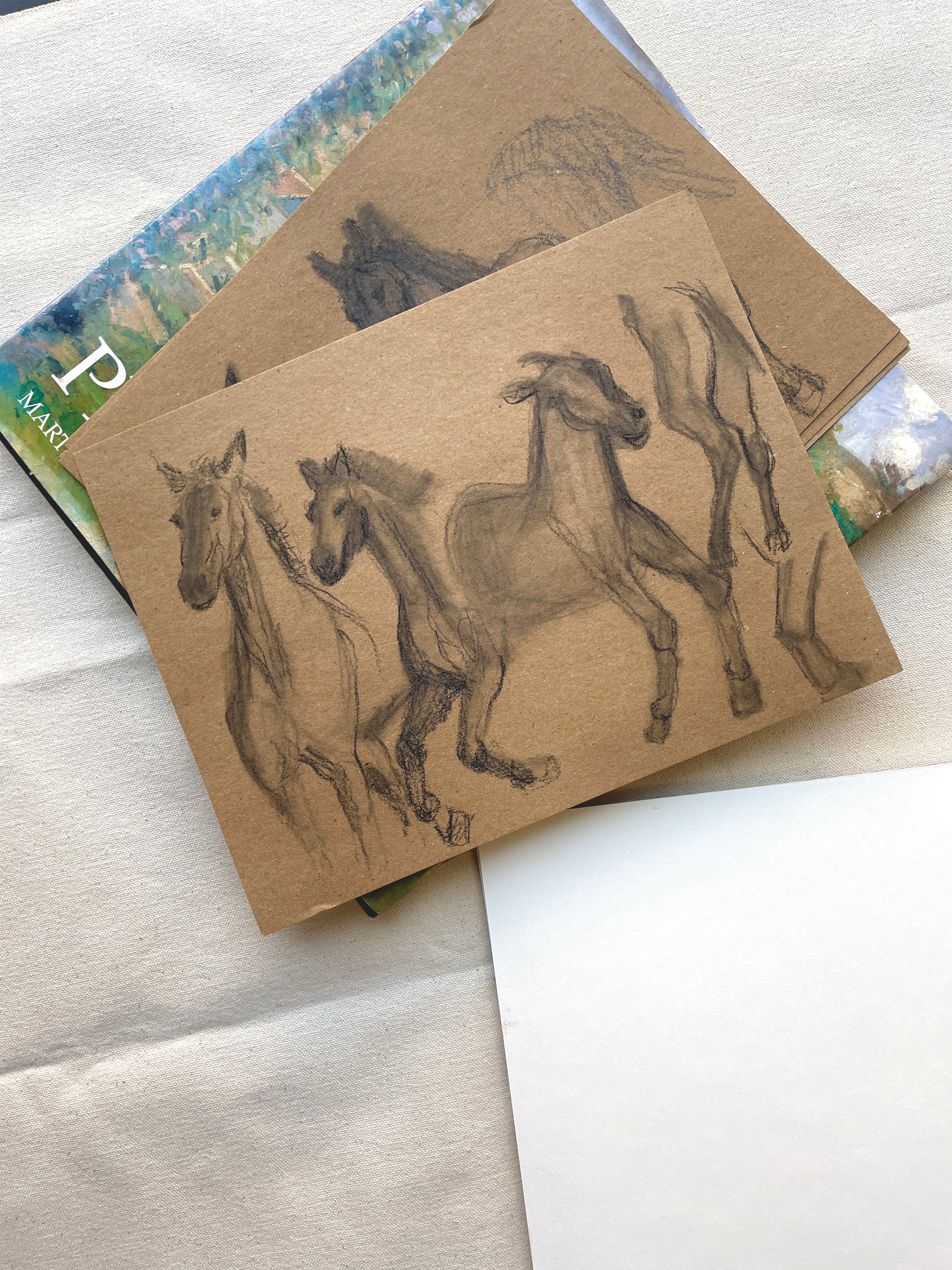 Charcoal sketch of galloping horses on natural craft paper